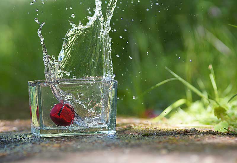 Rote Kugel fällt in ein Wasserglas, lernen von kurzer Belichtungszeit. 